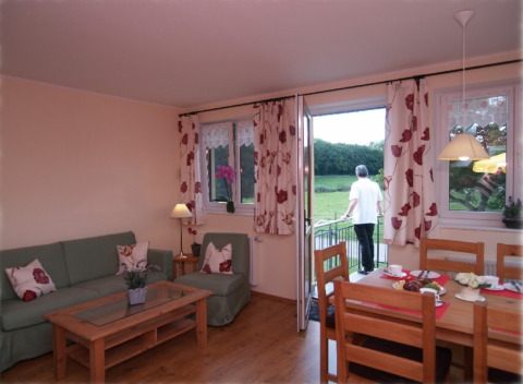 Cozy Eifelidyll glamping in Rhineland-Palatinate with living room, dining table, and balcony overlooking nature.