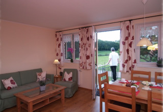 Eifelidyll luxe kampeeraccommodatie Rijnland-Palts met woonkamer, eettafel en uitzicht op natuur vanaf balkon.