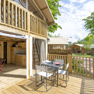 Terrasse eines Airlodges im Trasimeno Glamping Resort mit Essbereich und Blick auf andere Glamping-Unterkünfte.