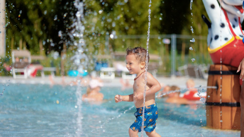 Un niño juega en una piscina con fuentes de agua en Trasimeno Glamping Resort – Airlodges Umbrië.
