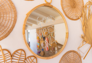 Miroir rond en osier avec la phrase 'GOOD VIBES ONLY' au Trasimeno Glamping Resort, décoration bohème.