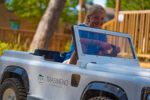 Bambino guida un’auto giocattolo al Trasimeno Glamping Resort, parte di Vacanze col Cuore in Italia.
