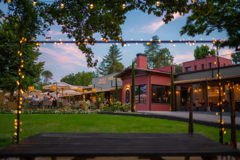 Buitenrestaurant bij Trasimeno Glamping Resort met sfeerverlichting, groene grasvelden en zitplaatsen.