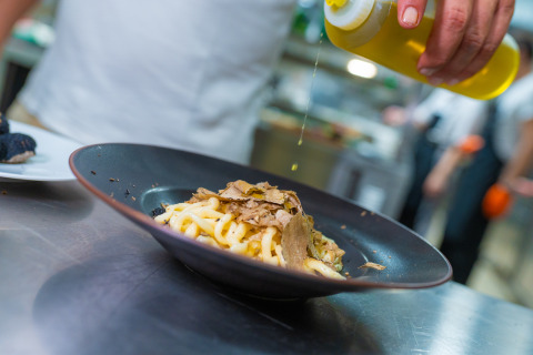 En kok hælder olie over frisklavet pasta med trøfler på en restaurant nær Trasimeno Glamping Resort.