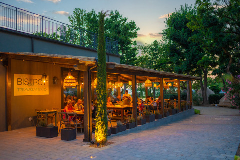 Sunset dining at the outdoor bistro of Trasimeno Glamping Resort Umbrië, guests enjoy cozy lights and nature.