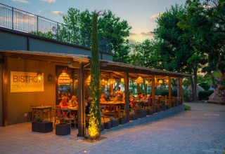 Sunset dining at the outdoor bistro of Trasimeno Glamping Resort Umbrië, guests enjoy cozy lights and nature.