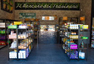 Store at Trasimeno Glamping Resort offering Italian specialties and modern shelving near the reception area.