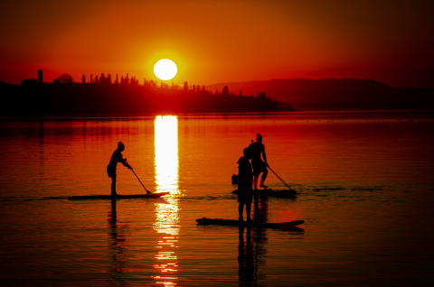 Sonnenuntergang am See bei Trasimeno Glamping Resort, Gäste paddeln entspannt auf dem Wasser im Abendlicht.