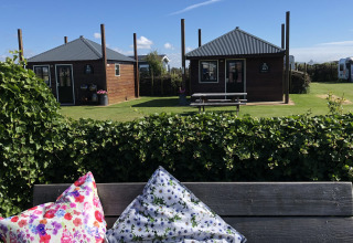 Glamping accommodation with wooden cabins and colorful pillows, Camping Duinzoomhoeve, North Holland.