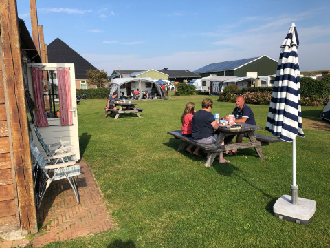 Familie nyder udendørs picnic ved campingpladsen Camping Duinzoomhoeve – Hooiberghut glamping i Noord-Holland.