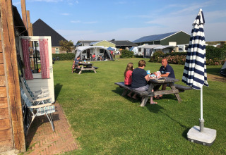 Familie entspannt sich beim Picknick im Freien auf dem Camping Duinzoomhoeve – Hooiberghut Glamping in Noord-Holland.