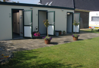Sanitairgebouw buiten bij Camping Duinzoomhoeve – Hooiberghut glamping Noord-Holland, met bloempotten.