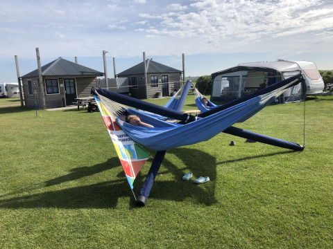 Twee personen ontspannen in hangmatten bij Camping Duinzoomhoeve – Hooiberghut glamping in Noord-Holland.