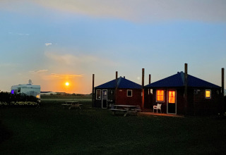 Sonnenuntergang und beleuchtete Hütten bei Camping Duinzoomhoeve – Hooiberghut Glamping in Noord-Holland.