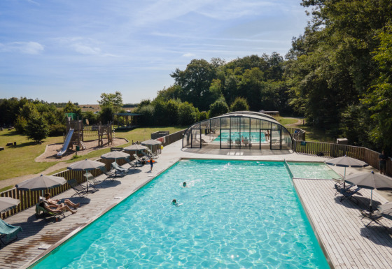 Piscina all'aperto e area giochi al Village Huttopia Senonches - Glamping Val de Loire immersi nella natura.