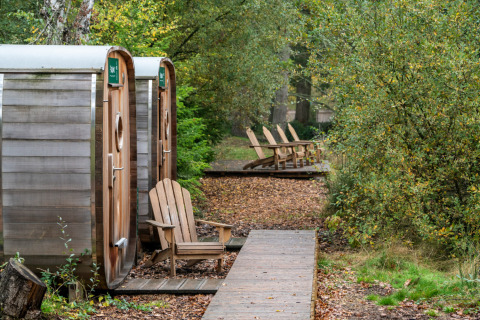 Cabanes rondes et chaises en bois à Village Huttopia Senonches, glamping en pleine nature dans le Val de Loire.