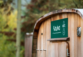Sauna en bois à Village Huttopia Senonches - Glamping Val de Loire, panneau indiquant 65°C.