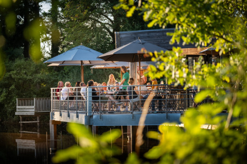 Repas en plein air sur une terrasse entourée de verdure à Village Huttopia Senonches - Glamping Val de Loire.
