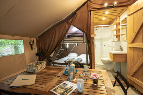 Glampingaccommodatie in Village Huttopia Senonches - Glamping Val de Loire met eettafel, stapelbed en badkamer.