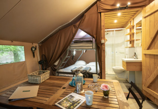 Glampingaccommodatie in Village Huttopia Senonches - Glamping Val de Loire met eettafel, stapelbed en badkamer.