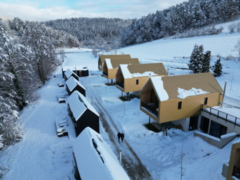 Blick auf Adventure Camp Schnitzmühle: Tiny House-Unterkünfte im verschneiten Bayerischen Wald.