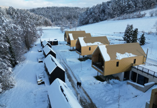 Aerial view of Adventure Camp Schnitzmühle - Tiny House Bavarian Forest glamping in winter snow.
