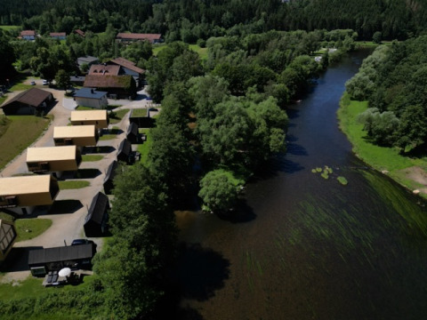 Aerial view of Adventure Camp Schnitzmühle glamping with tiny houses along a river in the Bavarian Forest.
