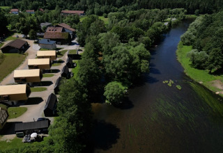 Aerial view of Adventure Camp Schnitzmühle glamping with tiny houses along a river in the Bavarian Forest.