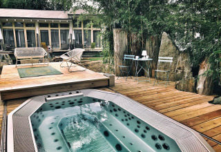 Terrazza all'aperto con vasca idromassaggio e sedie all’Adventure Camp Schnitzmühle, Tiny House Foresta Bavarese.