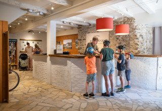 Receptie bij Huttopia Beaulieu sur Dordogne met gezinnen en kinderen met fietshelmen, klaar voor glamping.