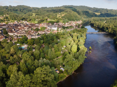 Vista aérea de Huttopia Beaulieu sur Dordogne, sitio de glamping y camping rodeado de vegetación y río.