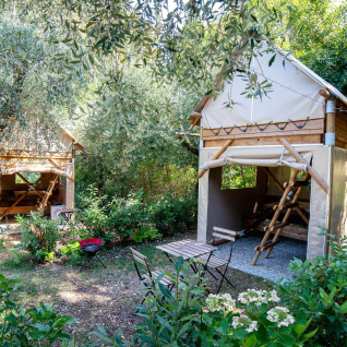 Twee knusse glampinghutten bij Sivinos Camping Boutique aan het Gardameer, omgeven door groen.