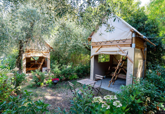 Two cozy glamping huts at Sivinos Camping Boutique, Lake Garda, surrounded by lush greenery and trees.