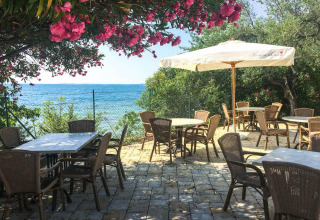 Espace repas extérieur au Sivinos Camping Boutique, vue sur le lac de Garde, fleurs et parasols.