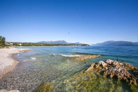 Rotsachtige oever en helder water bij het Gardameer bij Vacanze col Cuore: Sivinos Camping Boutique - Glamping Gardameer.