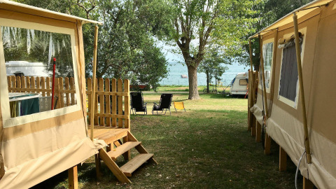 Glamping-indkvartering ved søen med telte, campingvogn og stole hos Sivinos Camping Boutique ved Gardasøen.