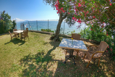 Gemütlicher Außensitzbereich mit Seeblick und blühenden Bäumen bei Sivinos Camping Boutique am Gardasee.