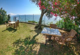 Outdoor seating area with scenic lake view and flowering tree at Sivinos Camping Boutique - Glamping Gardameer.