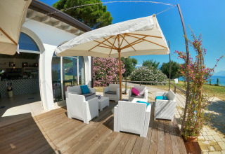 Zona lounge exterior con muebles blancos y sombrilla en Sivinos Camping Boutique Glamping Lago de Garda.