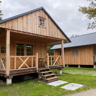 Deux chalets en bois au Camping & Chaletparc De Uitwijk – Lodges Noord-Brabant entourés de verdure.