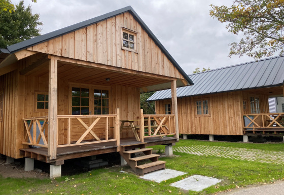 To træhytter på Camping & Chaletparc De Uitwijk – Lodges Noord-Brabant med grønne omgivelser.