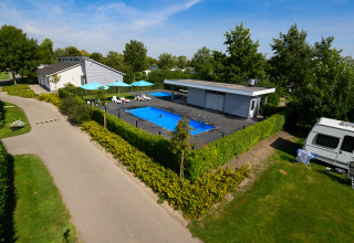 Camping & Chaletparc De Uitwijk – Lodges Noord-Brabant features a pool, relaxation area, and caravan park in greenery.