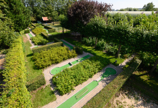 Minigolfbanen omringd door groene hagen bij Camping & Chaletparc De Uitwijk – Lodges Noord-Brabant.