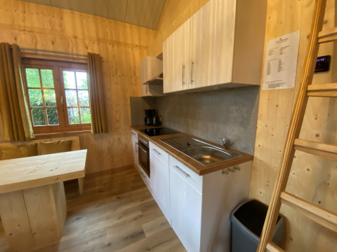 Moderne glamping keuken met houten wanden, raam, eettafel en trap bij Camping & Chaletparc De Uitwijk.