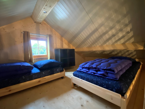 Accogliente camera mansardata con due letti singoli in legno presso Camping & Chaletparc De Uitwijk, Noord-Brabant.