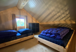 Knusse zolderkamer met twee eenpersoonsbedden en houten interieur bij Camping & Chaletparc De Uitwijk, Noord-Brabant.