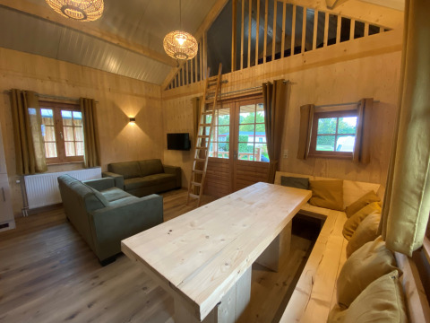 Hyggelig lodges stue med træmøbler, sofaer og hems på Camping & Chaletparc De Uitwijk i Noord-Brabant.