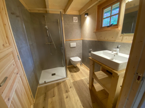 Modern bathroom with wood accents, large shower, toilet, and sink in glamping lodge at De Uitwijk, Noord-Brabant.