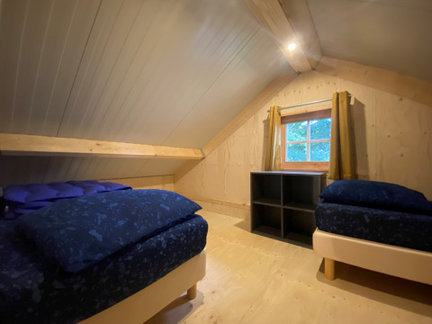 Chambre mansardée avec deux lits au Camping & Chaletparc De Uitwijk – Lodges Noord-Brabant, aux Pays-Bas.