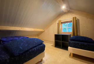 Dormitorio abuhardillado con dos camas en Camping & Chaletparc De Uitwijk – Lodges Noord-Brabant, Países Bajos.